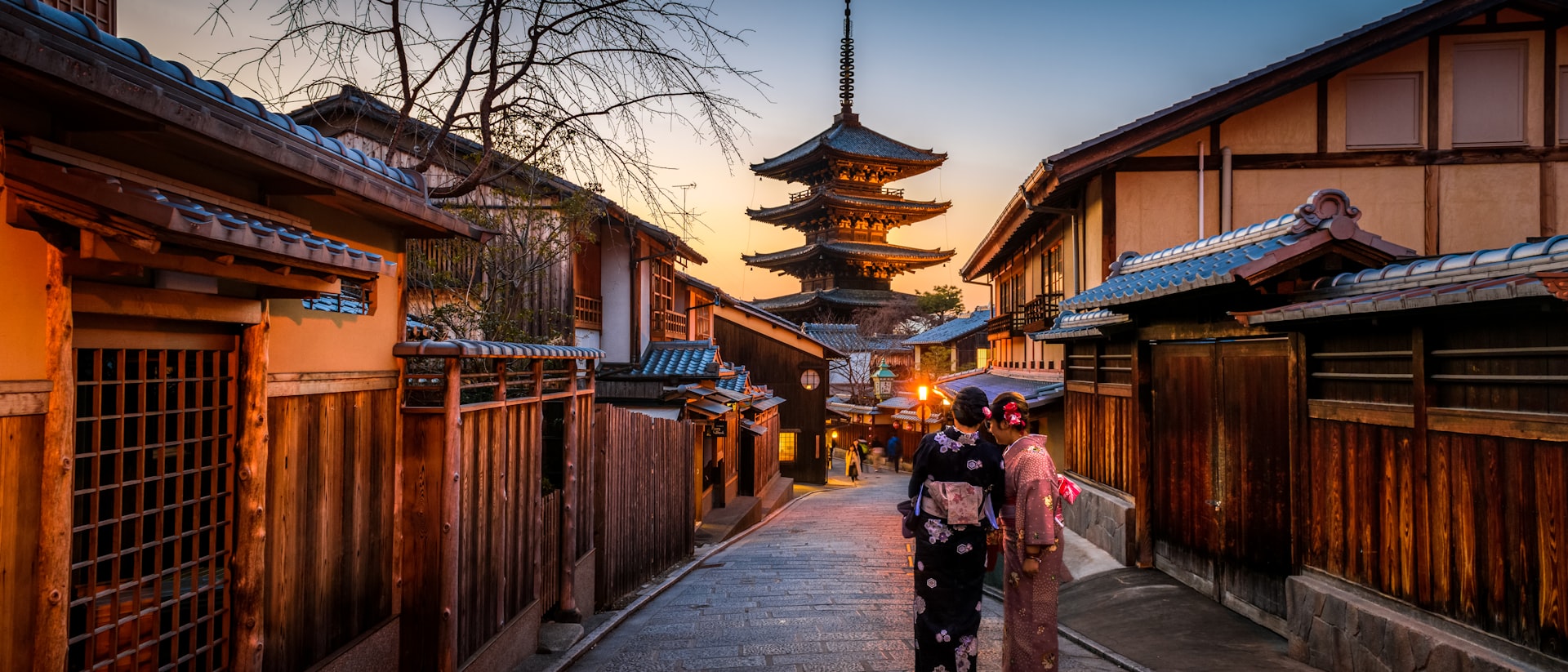 Neon-lit Tokyo street at dusk with the bullet train track visible above traditional lanterns