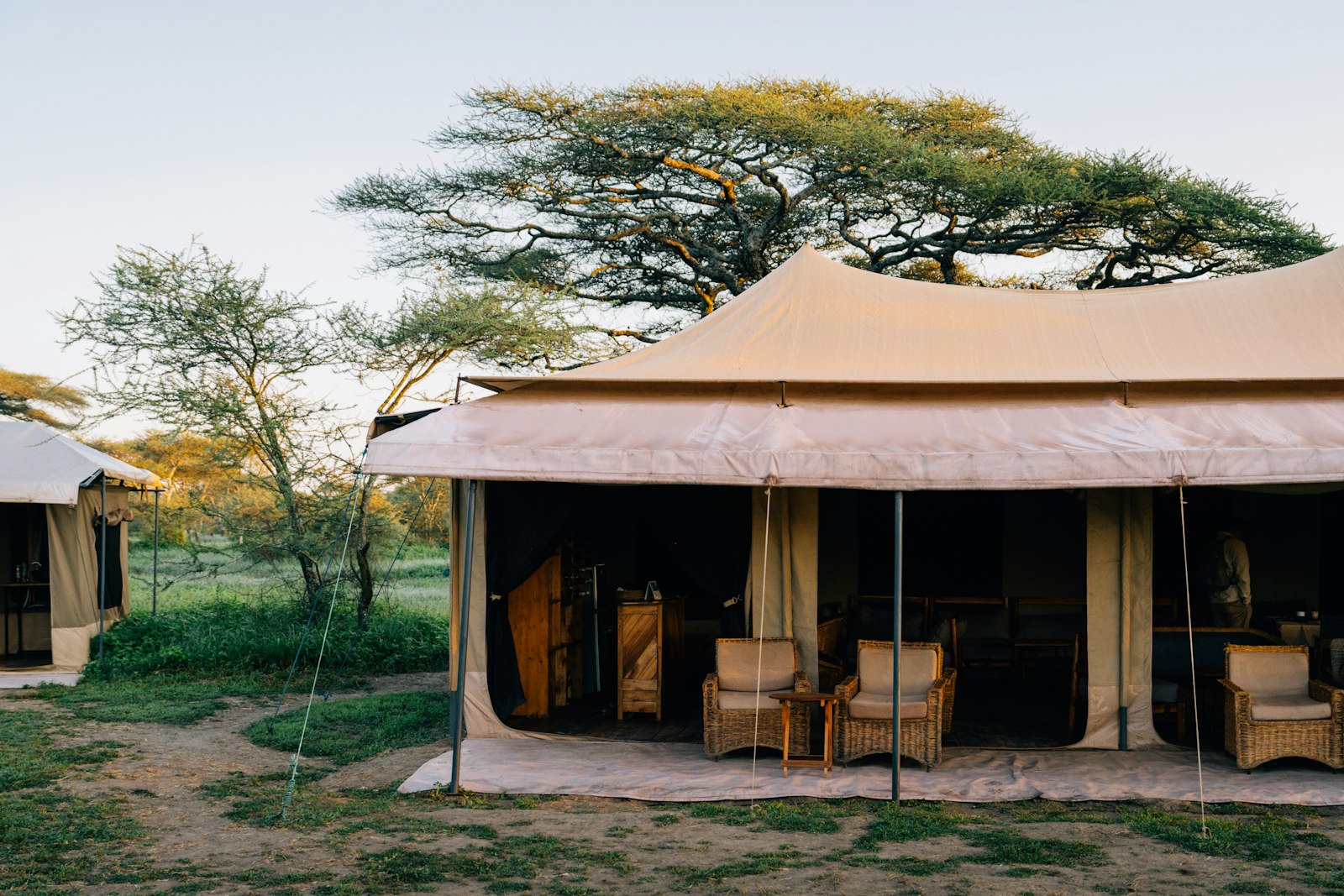 Luxury tented camp at sunset on the African plains, with elephants in the distance