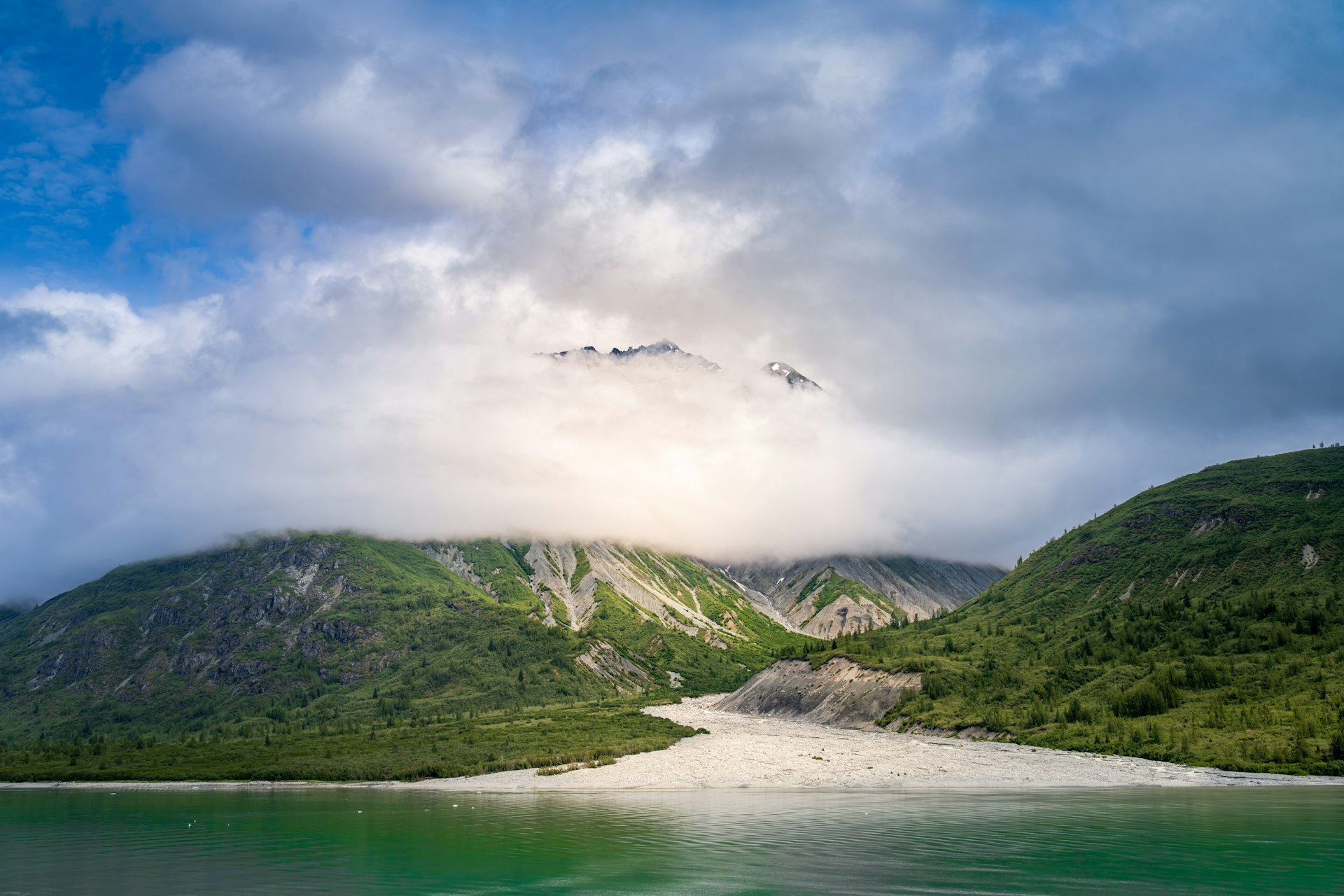 Massive Alaskan glacier flowing between snow-capped mountain ranges