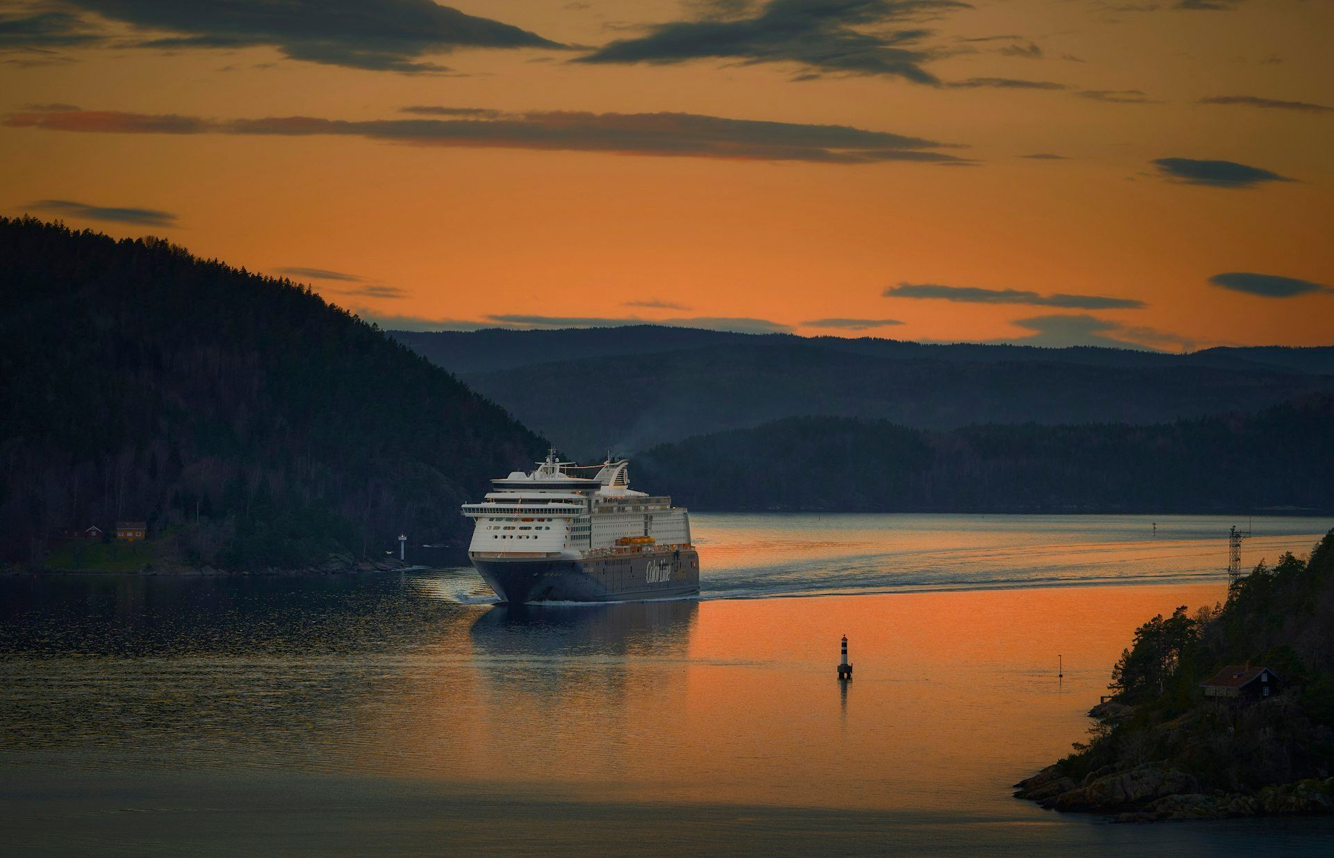 Hurtigruten ship sailing along the Norwegian coast with mountains in the background