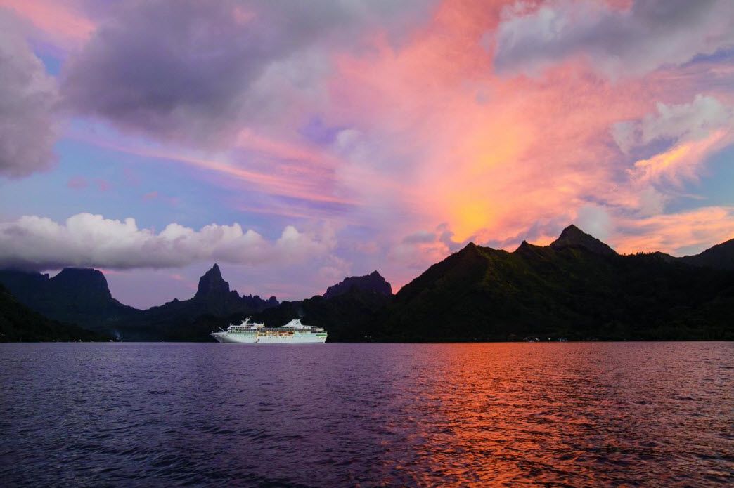Paul Gauguin cruise ship anchored in turquoise South Pacific waters near a tropical island